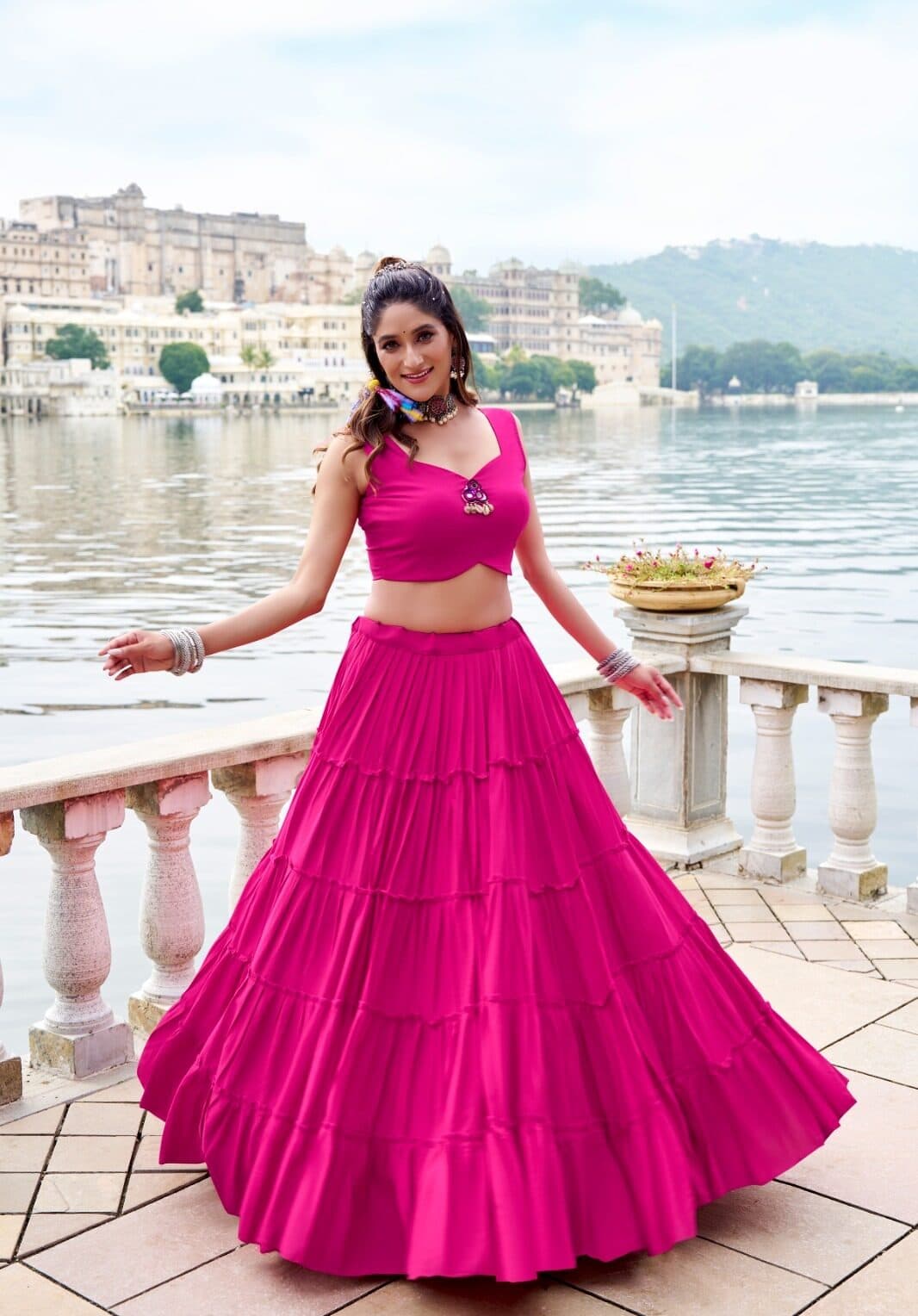 Model turning in a rani pink tiered rayon lehenga with a mirror-work blouse