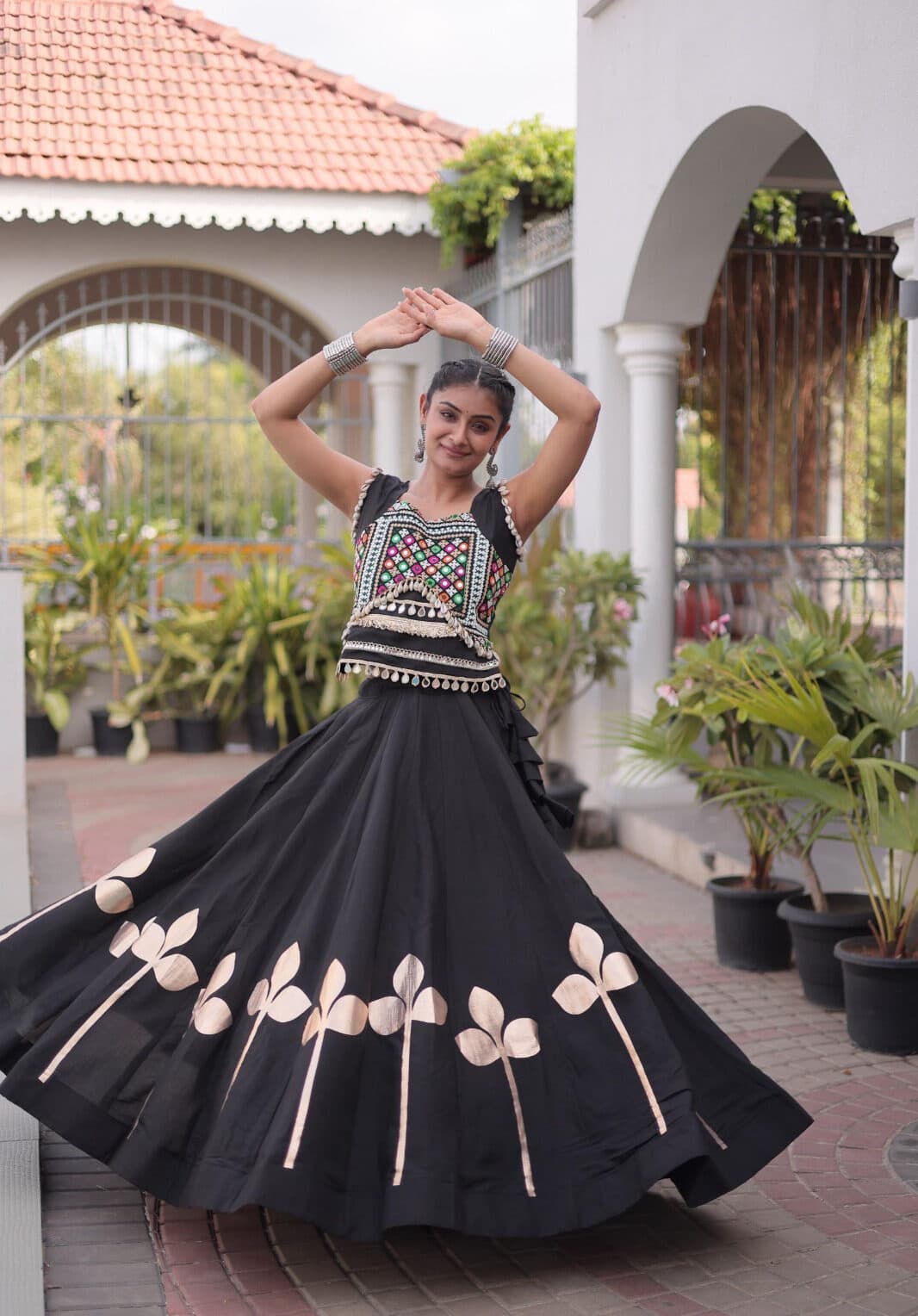 Model dancing in a black Roman silk chaniya choli with cream gota leaf work around the hem